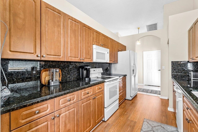 kitchen featuring a textured ceiling, decorative backsplash, white appliances, and light wood-type flooring