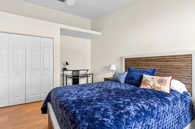 bedroom with ceiling fan, wood-type flooring, a textured ceiling, and a closet