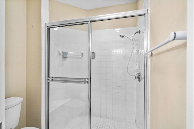 bathroom featuring toilet and a shower with shower door