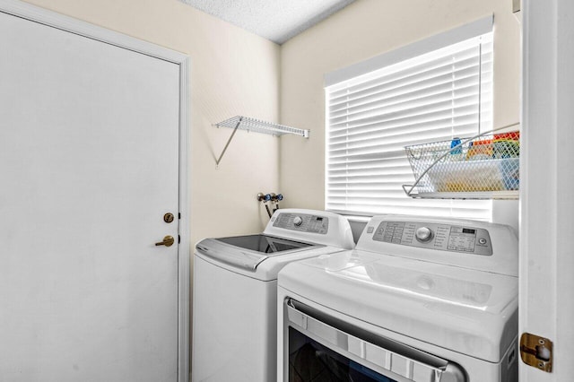 clothes washing area featuring washer and clothes dryer and a textured ceiling