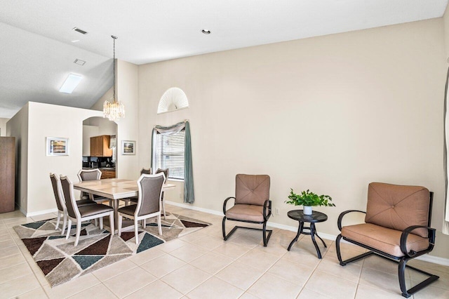 tiled dining space featuring high vaulted ceiling and a notable chandelier