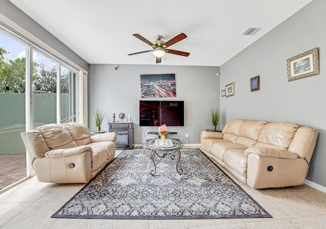 tiled living room featuring ceiling fan and a fireplace