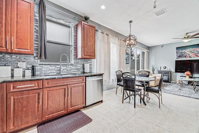 kitchen featuring dishwasher, sink, hanging light fixtures, dark stone counters, and ceiling fan with notable chandelier