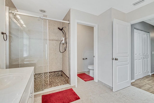 bathroom featuring vanity, hardwood / wood-style flooring, toilet, and a shower with shower door