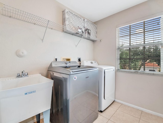 washroom featuring light tile patterned flooring, washing machine and dryer, and sink