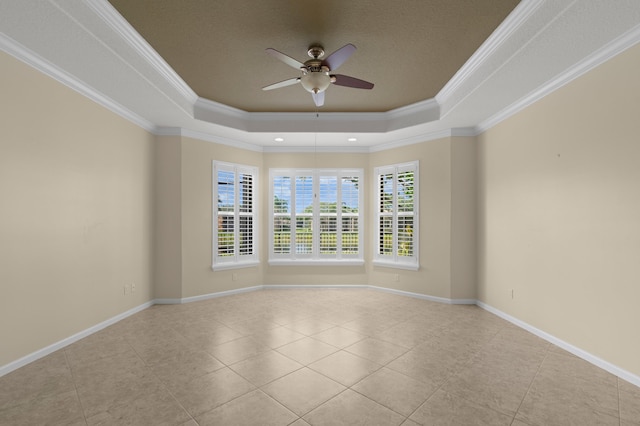 tiled spare room with a raised ceiling, a wealth of natural light, ornamental molding, and ceiling fan