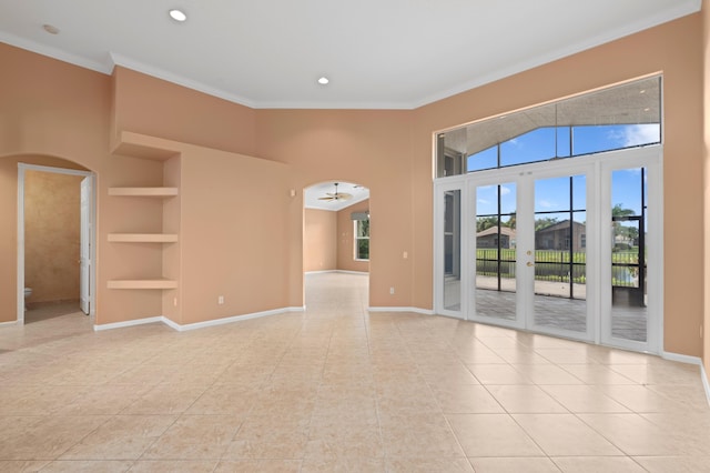 spare room featuring built in shelves, ceiling fan, french doors, light tile patterned floors, and ornamental molding