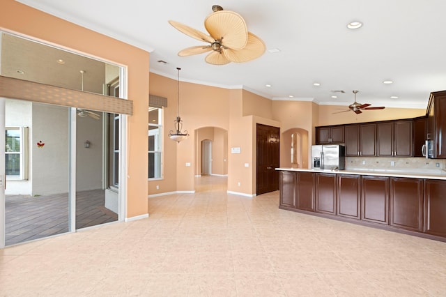 kitchen featuring decorative backsplash, appliances with stainless steel finishes, dark brown cabinetry, crown molding, and pendant lighting