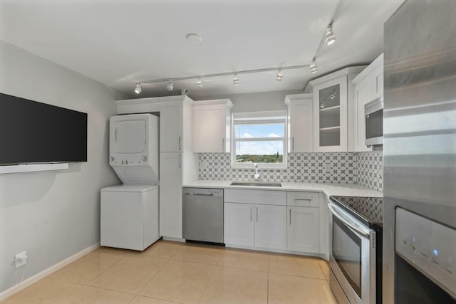 kitchen with sink, white cabinets, stacked washer and clothes dryer, and appliances with stainless steel finishes