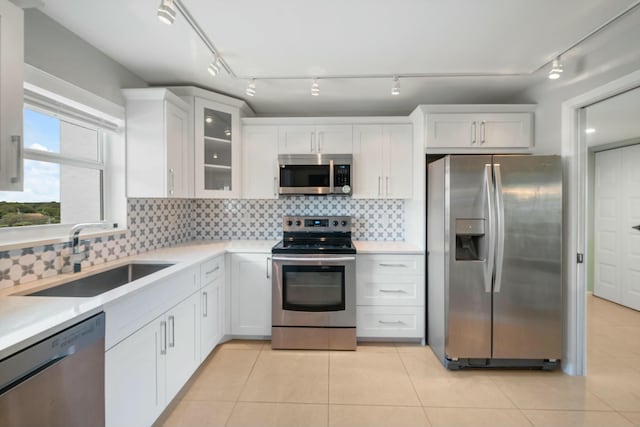 kitchen with stainless steel appliances, white cabinetry, tasteful backsplash, and sink