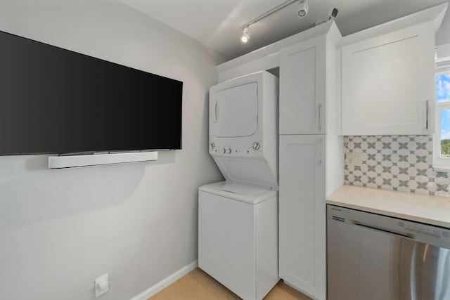 laundry area with rail lighting and stacked washing maching and dryer