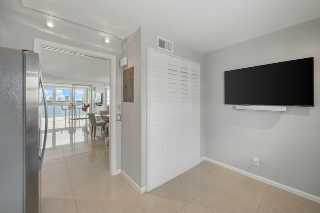 hall featuring rail lighting, electric panel, and light tile patterned flooring