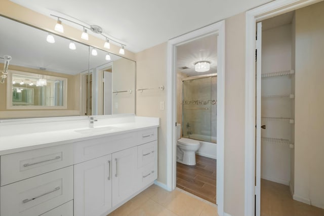 full bathroom with hardwood / wood-style floors, vanity, toilet, and enclosed tub / shower combo