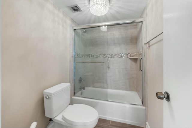 bathroom with wood-type flooring, combined bath / shower with glass door, and toilet