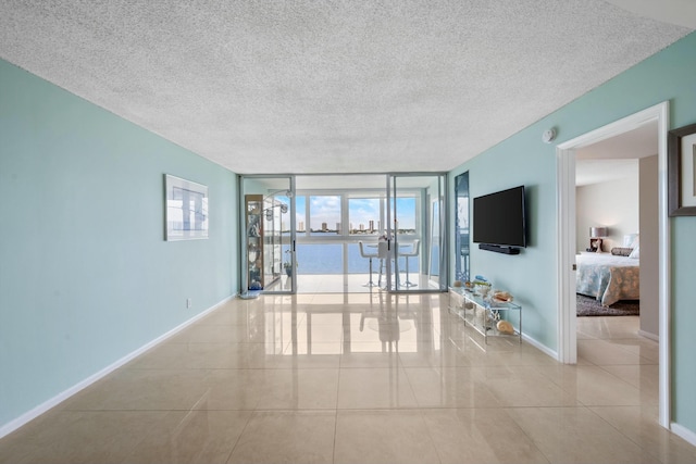 tiled empty room featuring a textured ceiling and expansive windows