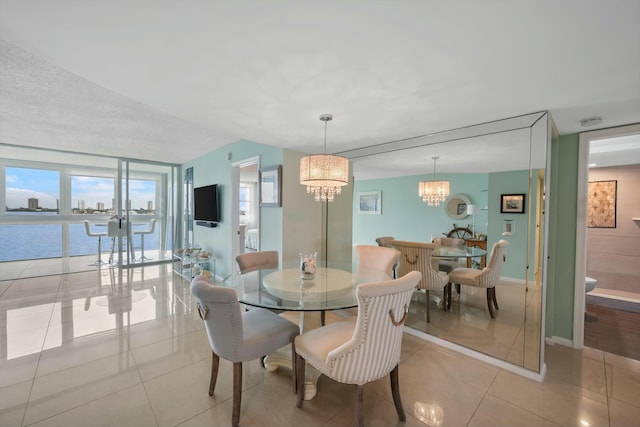 dining space with a chandelier, a water view, and light tile patterned flooring