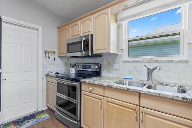 kitchen with light brown cabinets, sink, dark wood-type flooring, stainless steel appliances, and a textured ceiling