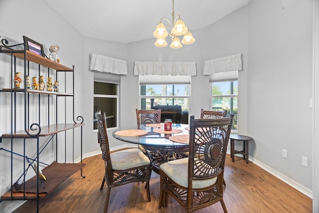 dining area with hardwood / wood-style flooring, vaulted ceiling, a textured ceiling, and an inviting chandelier