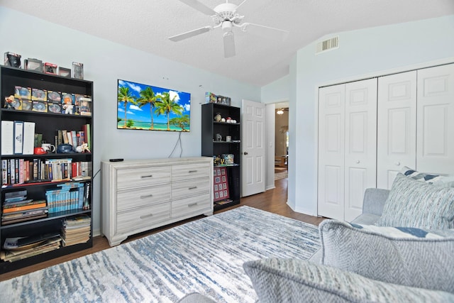 living area with dark hardwood / wood-style floors, ceiling fan, a textured ceiling, and vaulted ceiling