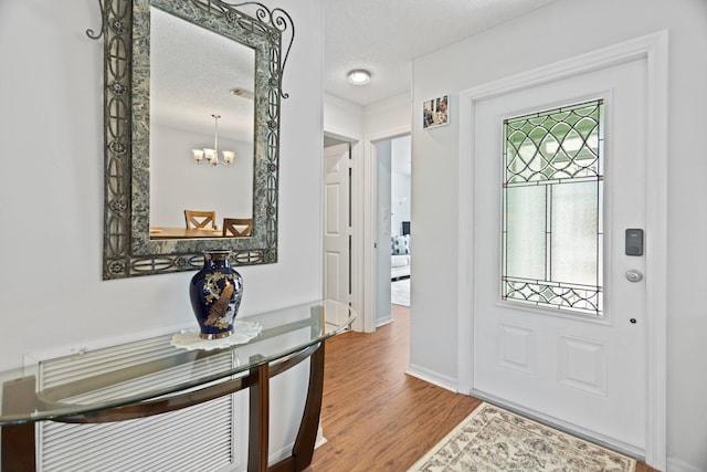 entryway featuring hardwood / wood-style floors, a textured ceiling, and an inviting chandelier