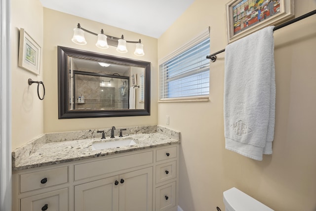 bathroom featuring a shower with door, vanity, and toilet