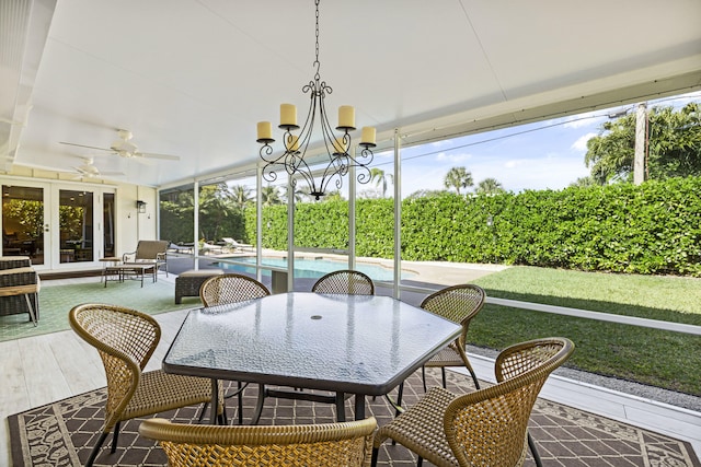 sunroom featuring ceiling fan with notable chandelier