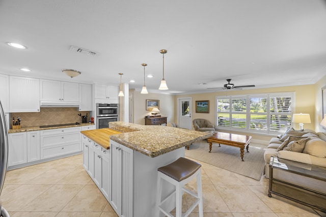 kitchen featuring ceiling fan, white cabinets, decorative light fixtures, and a kitchen island