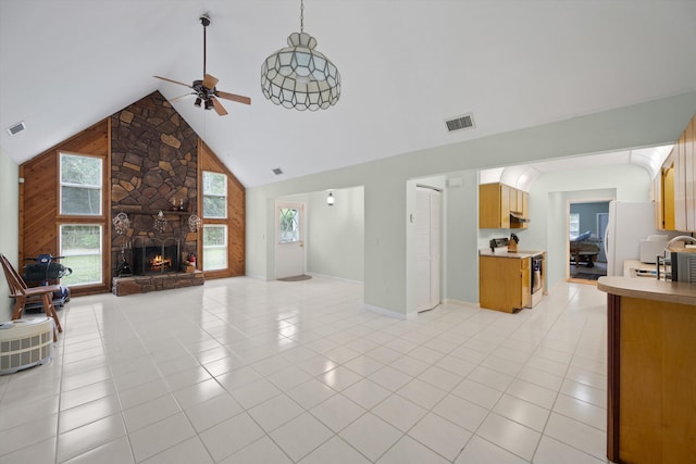 tiled living room with ceiling fan, a fireplace, and high vaulted ceiling