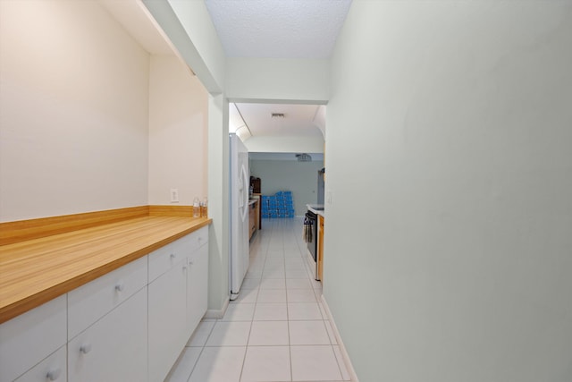 corridor with light tile patterned flooring and a textured ceiling