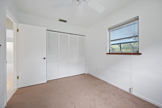 unfurnished bedroom featuring a closet, light colored carpet, and ceiling fan