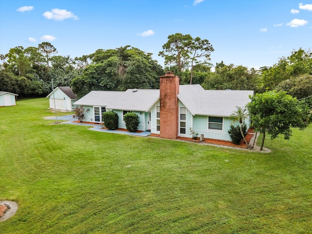 rear view of property featuring an outdoor structure and a lawn