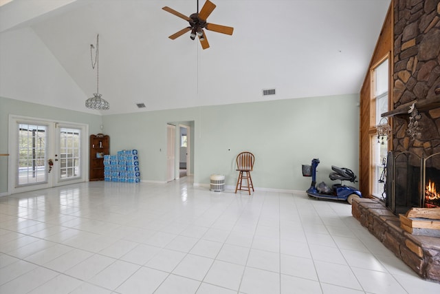 unfurnished living room featuring high vaulted ceiling, french doors, a stone fireplace, ceiling fan, and light tile patterned floors