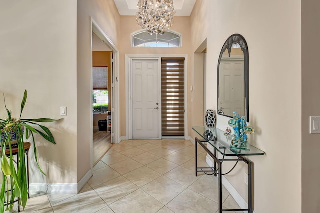 foyer entrance with plenty of natural light, light tile patterned floors, a high ceiling, and an inviting chandelier