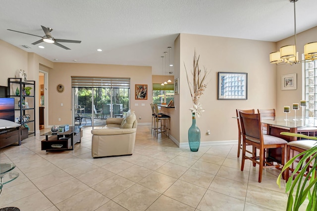 tiled living room featuring a textured ceiling and ceiling fan with notable chandelier