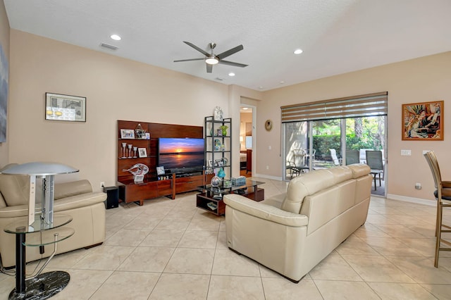 living room with ceiling fan, light tile patterned flooring, and a textured ceiling