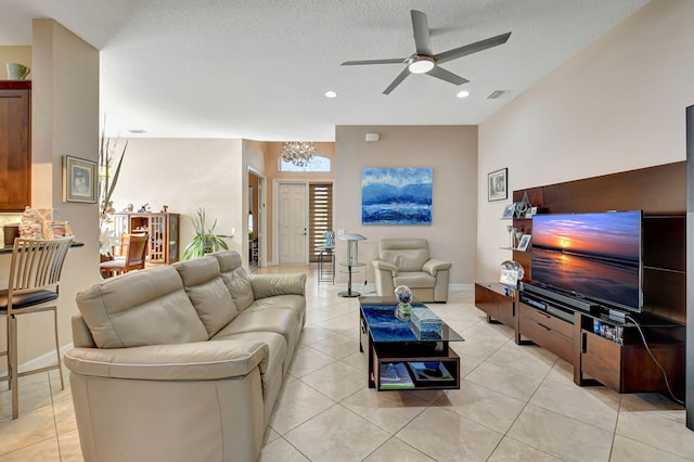 living room featuring ceiling fan, light tile patterned floors, and a textured ceiling