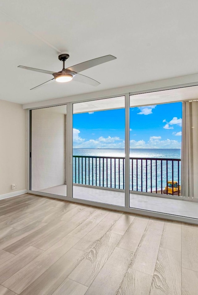 spare room featuring hardwood / wood-style flooring, ceiling fan, and a water view