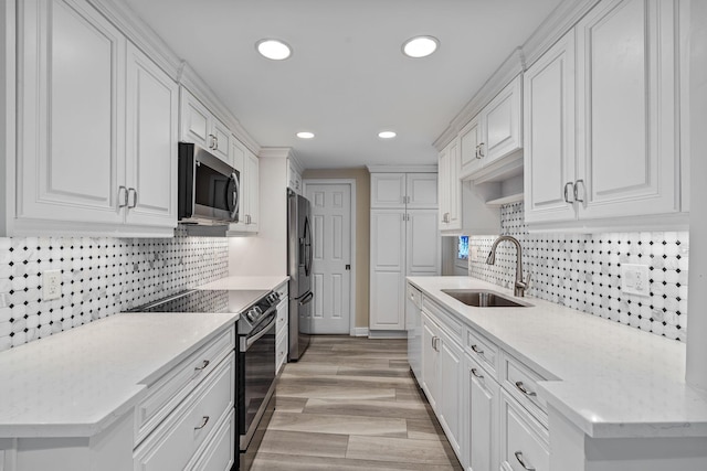 kitchen featuring stainless steel appliances, light stone countertops, sink, and white cabinets