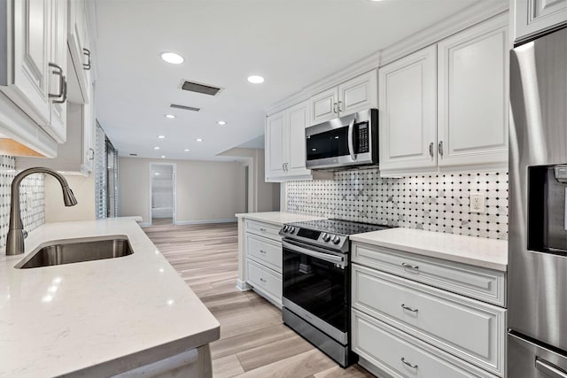 kitchen featuring sink, white cabinetry, tasteful backsplash, stainless steel appliances, and light stone countertops