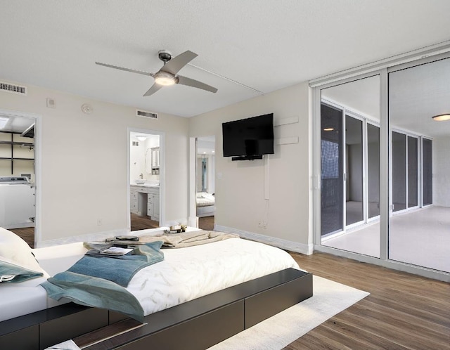 bedroom featuring washer / clothes dryer, ensuite bathroom, hardwood / wood-style floors, and ceiling fan