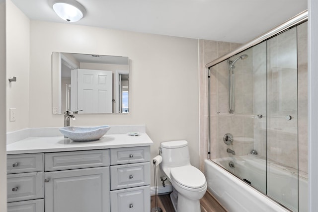 full bathroom with vanity, toilet, and combined bath / shower with glass door