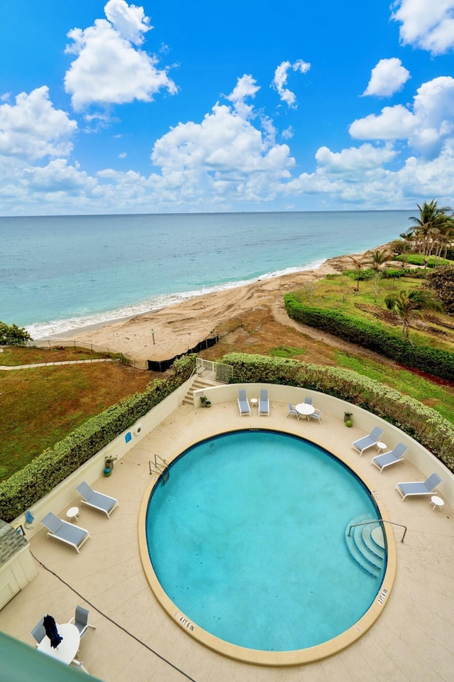 view of pool with a patio area, a beach view, and a water view