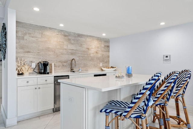 kitchen with sink, a breakfast bar area, a center island, white cabinets, and backsplash