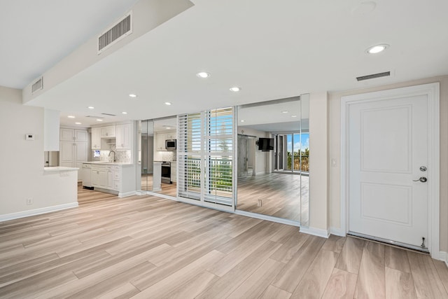 unfurnished living room featuring sink and light wood-type flooring