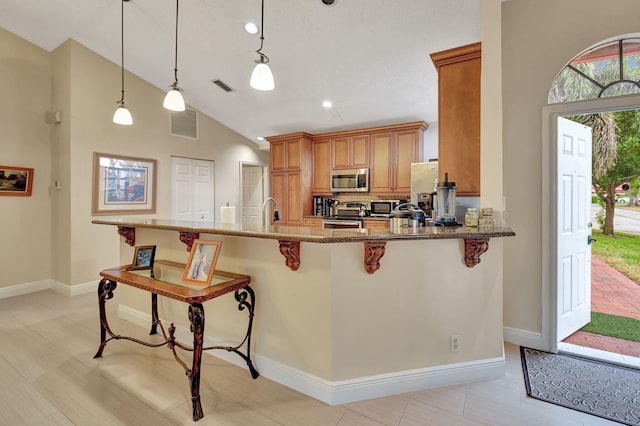 kitchen featuring stone counters, high vaulted ceiling, kitchen peninsula, decorative light fixtures, and appliances with stainless steel finishes