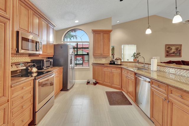 kitchen featuring backsplash, sink, vaulted ceiling, light stone countertops, and appliances with stainless steel finishes