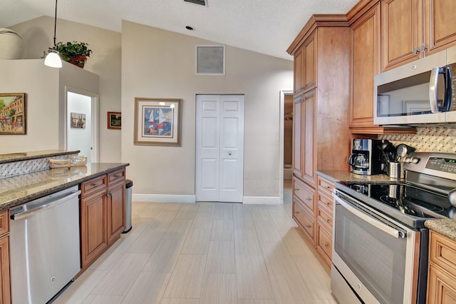 kitchen with stone counters, appliances with stainless steel finishes, high vaulted ceiling, and pendant lighting