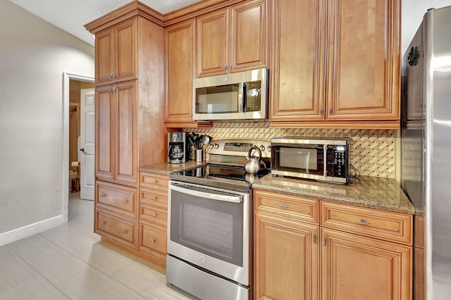 kitchen featuring light stone counters, light tile patterned floors, stainless steel appliances, and tasteful backsplash