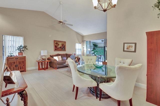 dining room featuring ceiling fan with notable chandelier and high vaulted ceiling