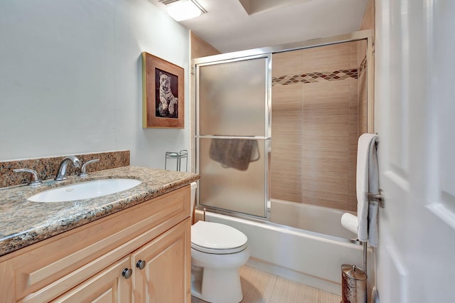 full bathroom featuring tile patterned floors, shower / bath combination with glass door, vanity, and toilet